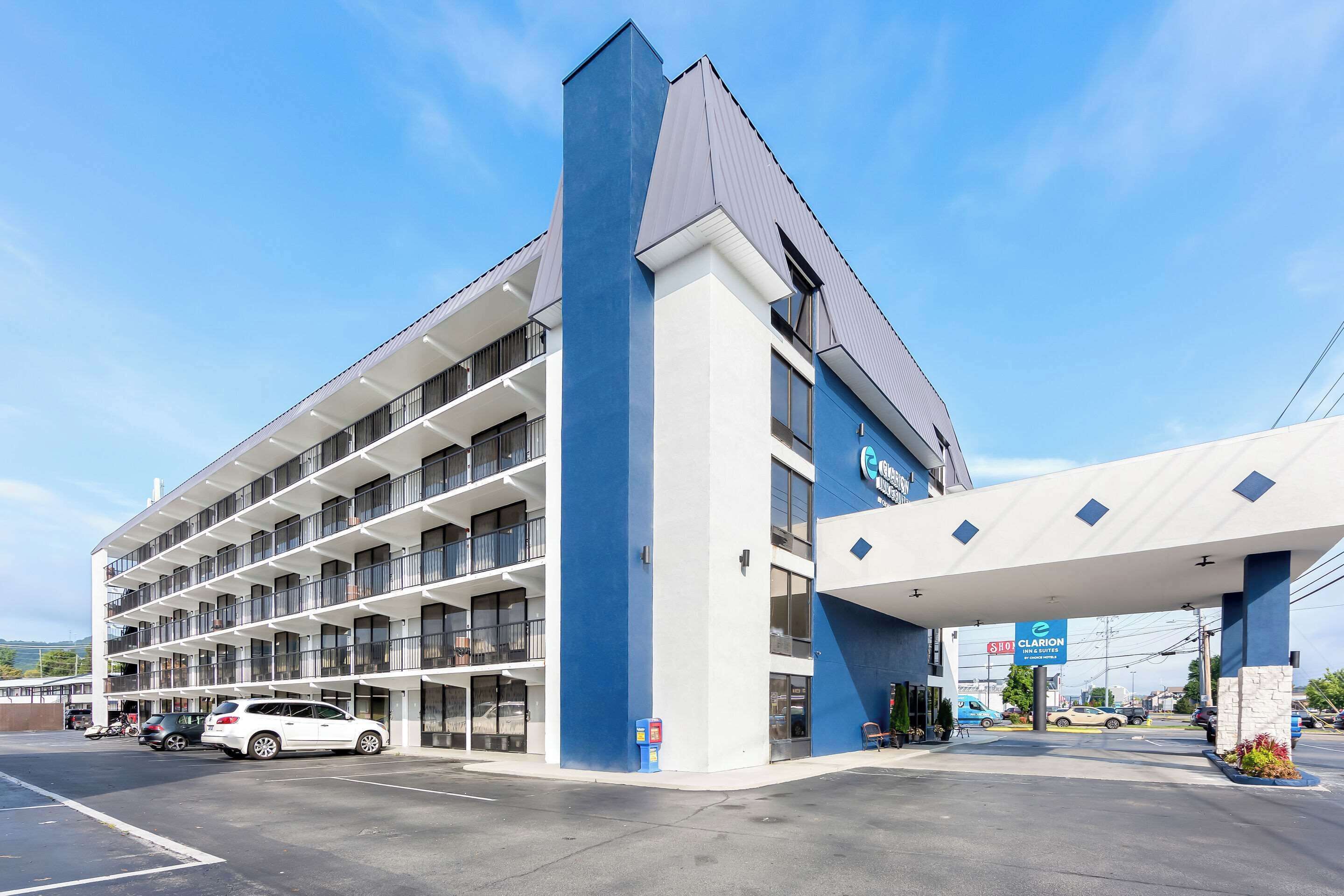 A multi-story hotel with a blue and white facade, a covered parking area, and a gas station sign.
