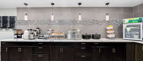 A modern kitchen with dark cabinets, a tiled backsplash, and various appliances including a coffee maker, toaster, and refrigerator.