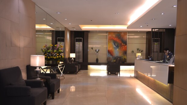A modern hotel lobby with a reception desk, seating area, and decorative plants. - Millenia Suites (Pasig)