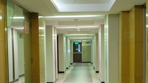 A long, well-lit hallway with glass doors on the left and wooden doors on the right, leading to various rooms. - Millenia Suites (Pasig)