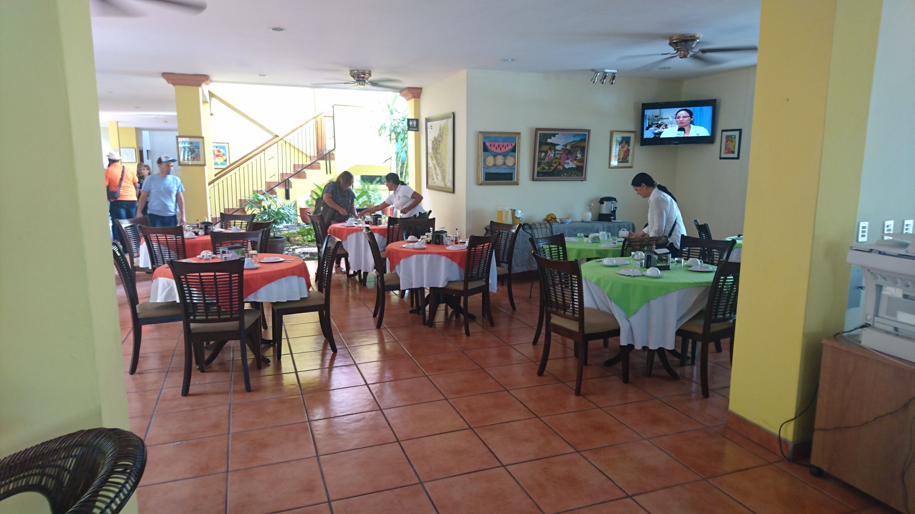 Un restaurante con varias mesas, sillas y un televisor en la pared.