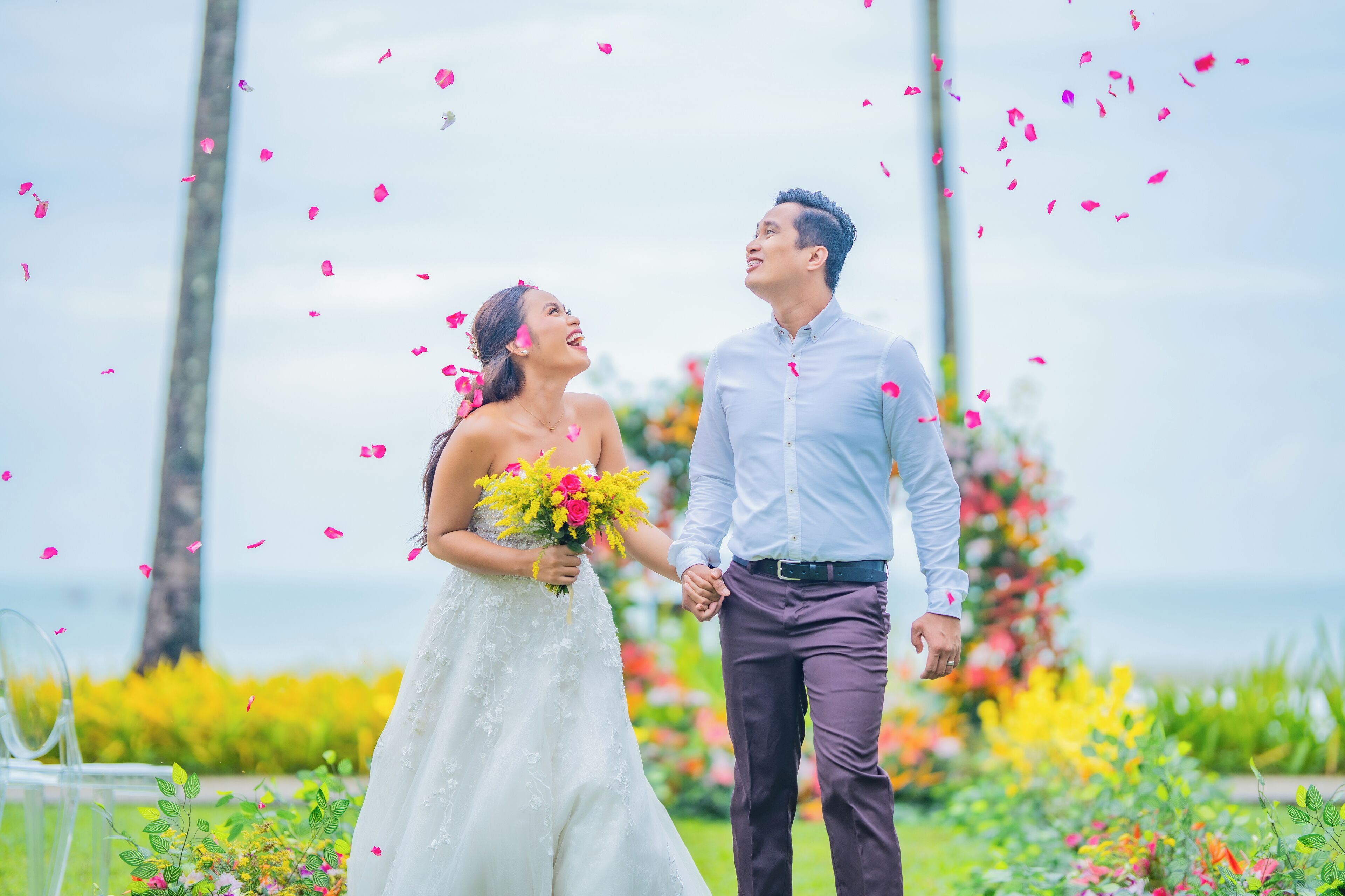Una pareja tomándose de las manos en un jardín con flores y follaje.