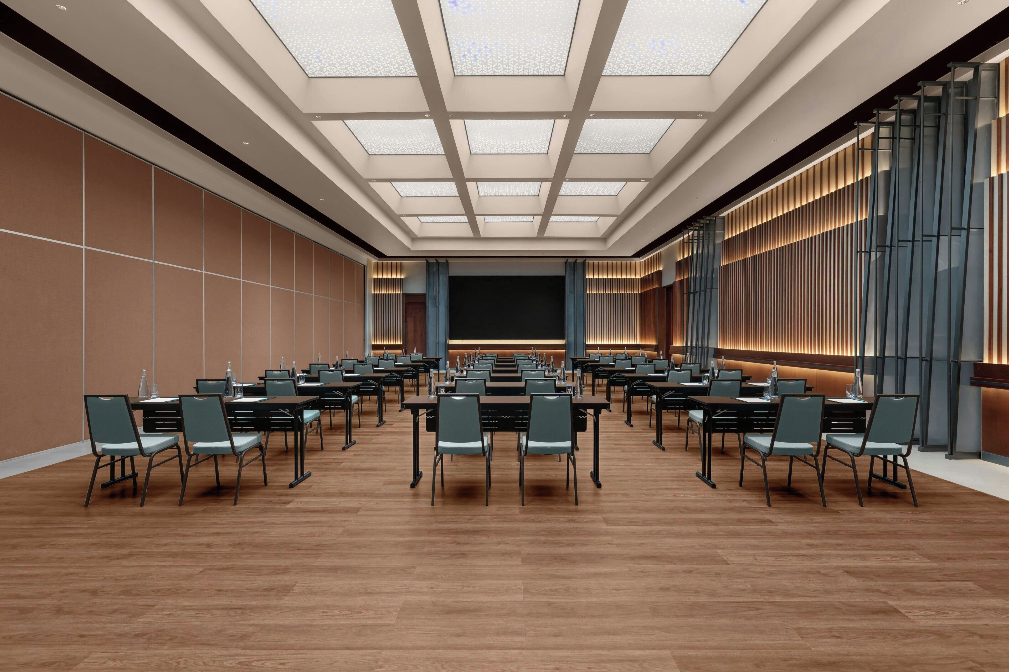 A conference room with a high ceiling, multiple tables, and chairs arranged for a meeting.