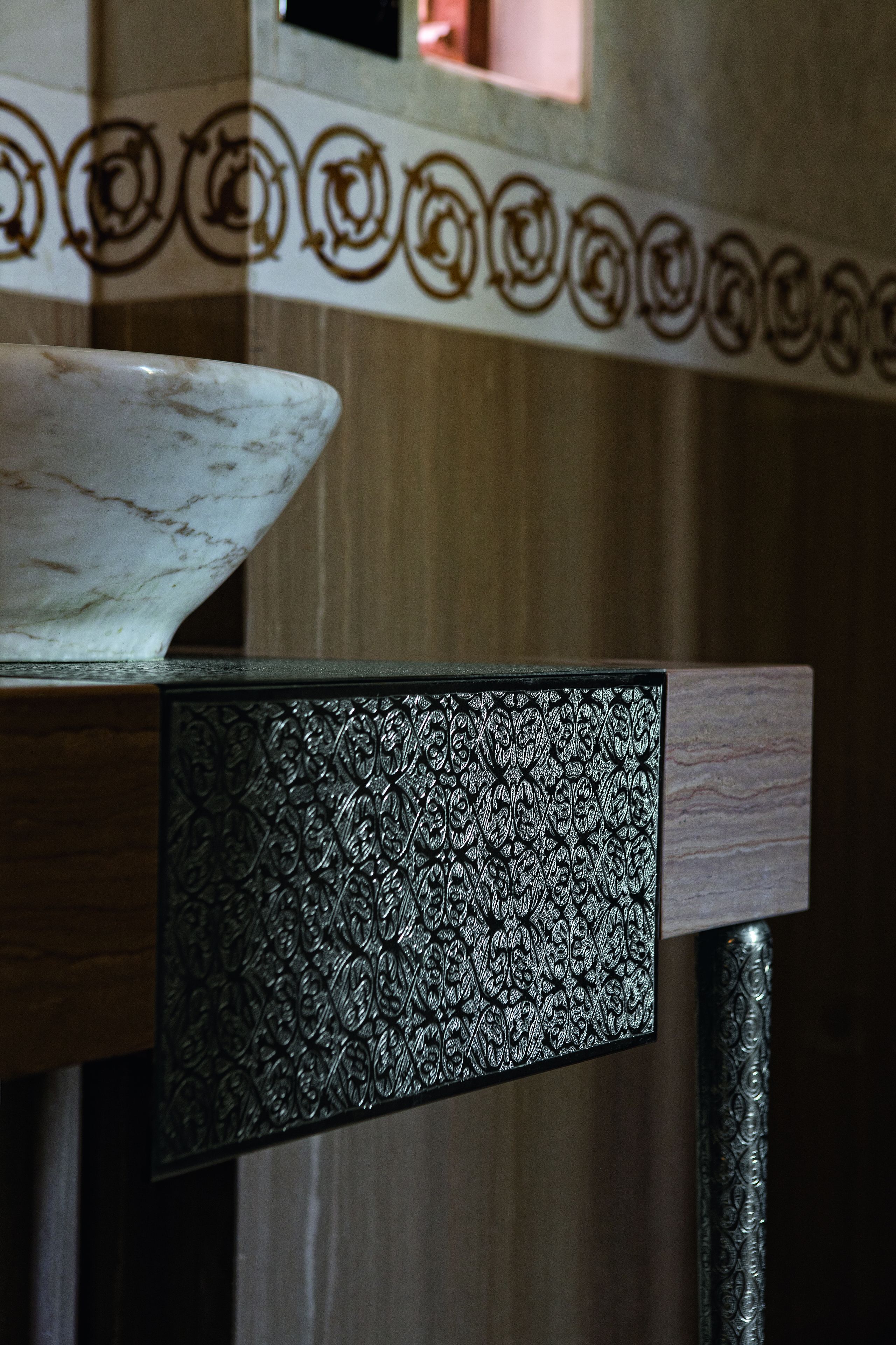 A marble bowl on a wooden table with a decorative panel.