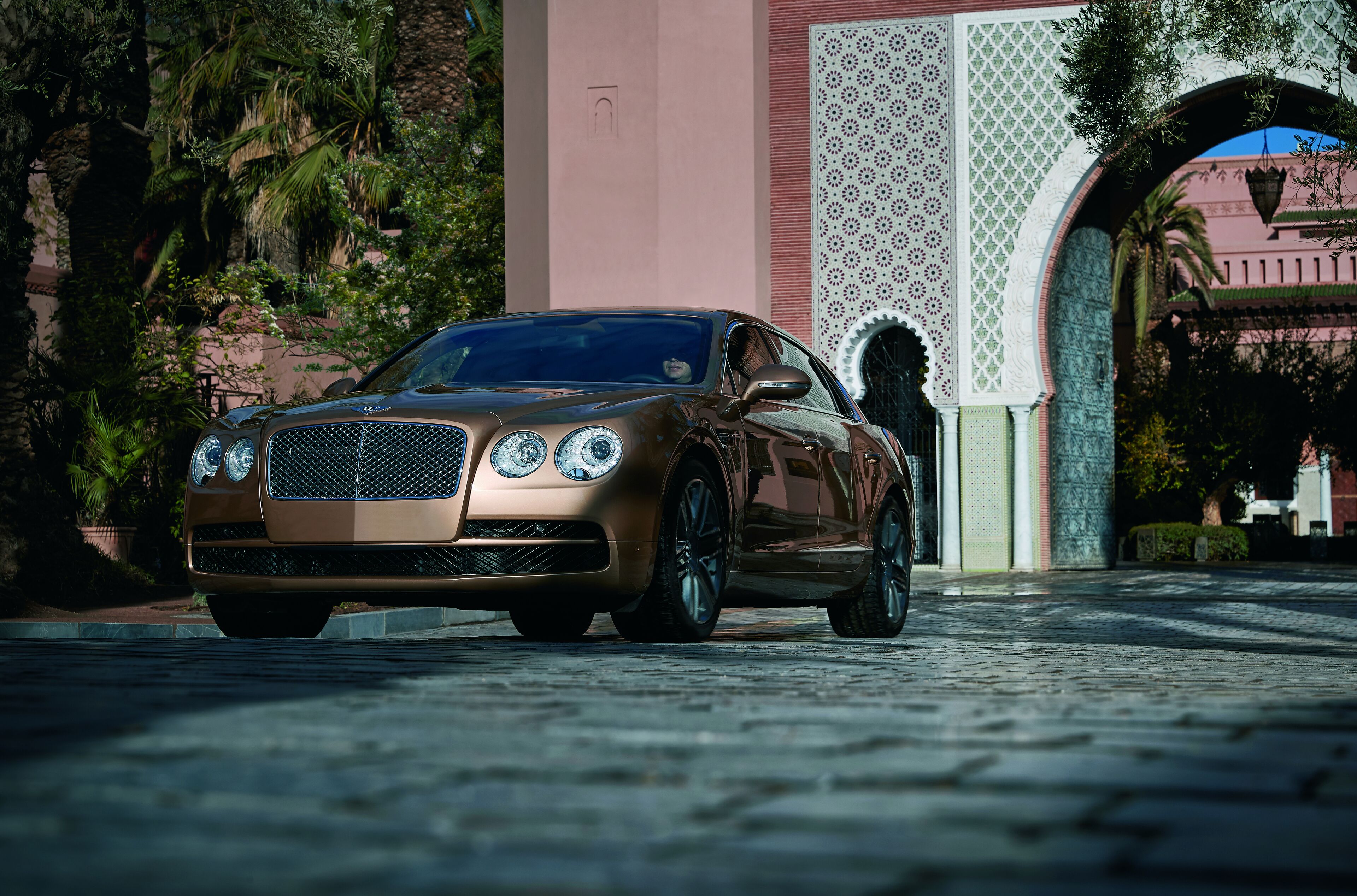 A luxury car parked in front of a building with intricate architectural details.