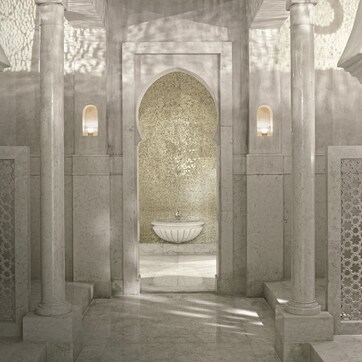 A corridor with a central fountain, flanked by columns and patterned walls.