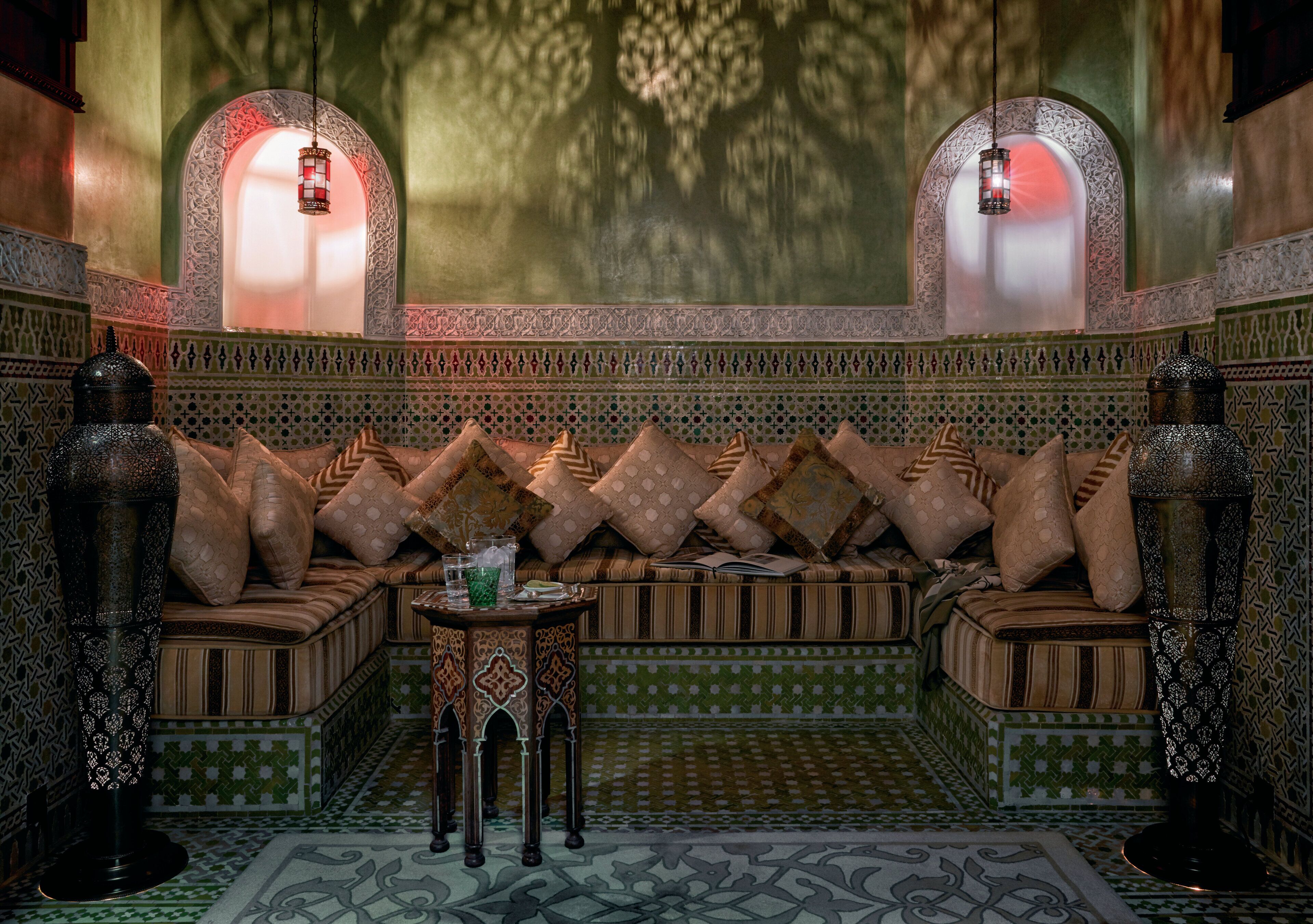 Un salon de style marocain, avec un canapé à motifs, des lampes décoratives et des décorations complexes en carreaux.