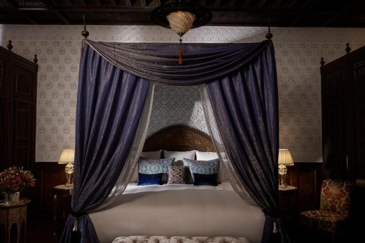 Une chambre à coucher avec un lit à baldaquin, un papier peint à motifs et un décor traditionnel.