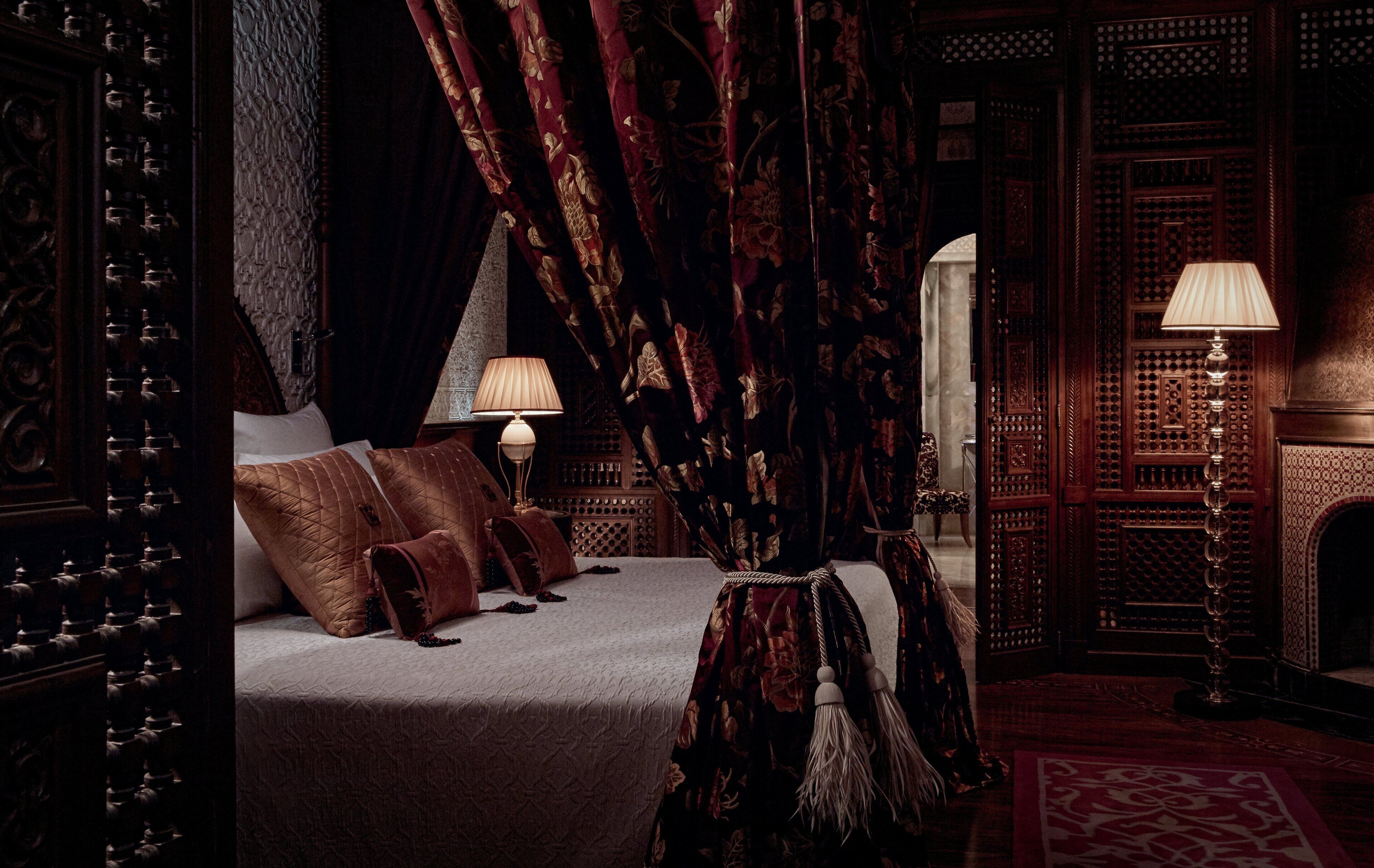 A luxurious bedroom with a large bed, ornate curtains, and a decorative lamp.