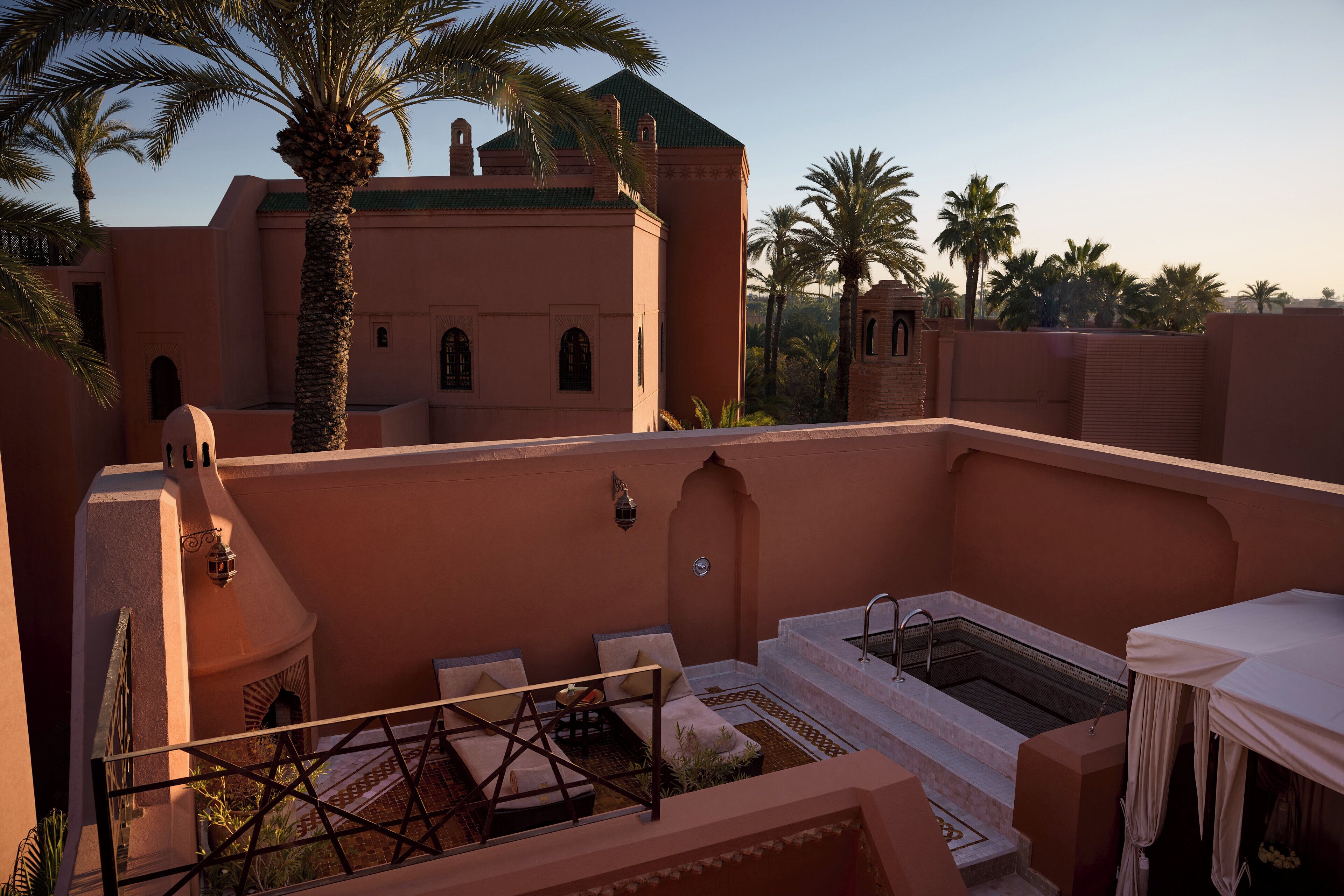Une terrasse sur le toit avec un espace salon, un jacuzzi et une vue sur les palmiers et les bâtiments.