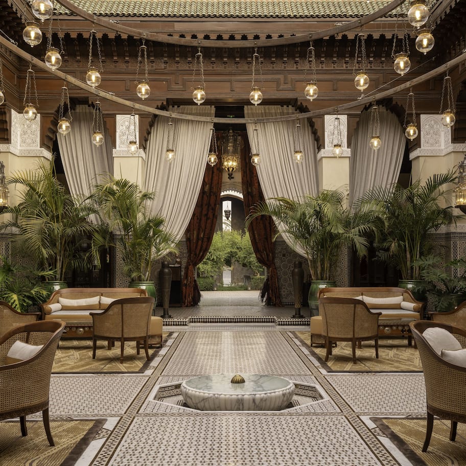 A luxurious lobby with ornate decor, hanging lanterns, and a central seating area with sofas and chairs.
