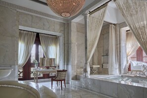 A luxurious bathroom with marble walls, a bathtub, and a vanity with a mirror.