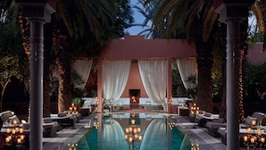 Zona junto a la piscina con un hogar, sillones de descanso y velas.