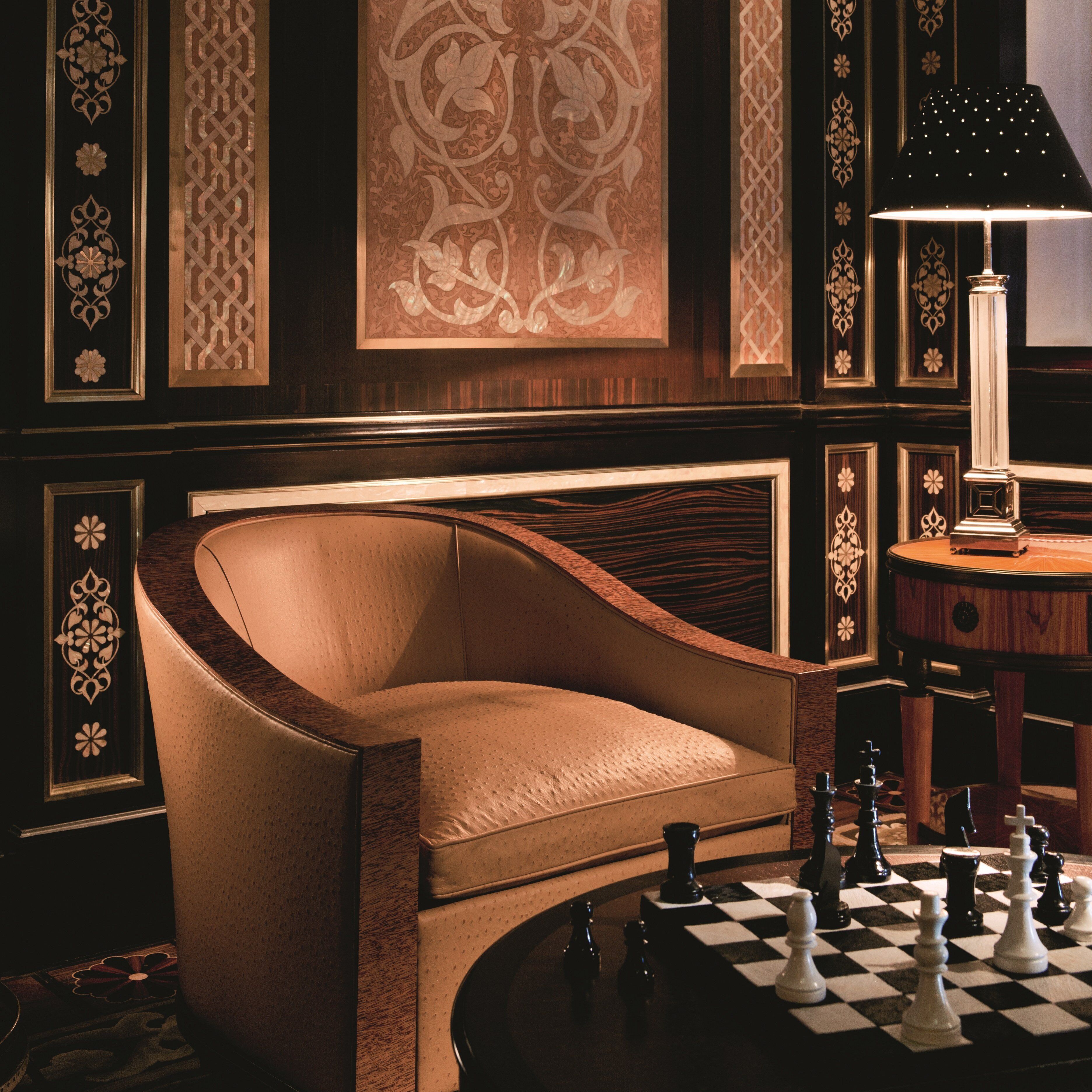 Une pièce comprenant un fauteuil en cuir aux formes arrondies, un jeu d’échecs et une lampe.
