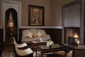 A cozy lounge area with a sofa, armchairs, a coffee table, and a fireplace.