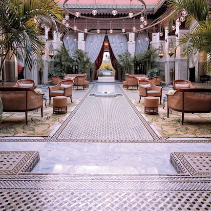 A luxurious lobby with a central fountain, ornate seating, and a tiled floor.