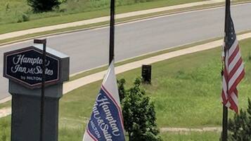 Un letrero del Hampton Inn & Suites, una bandera y vista de la calle con automóviles y edificios.