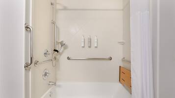 A bathroom with a bathtub, grab bars, a shower head, and a towel rack.