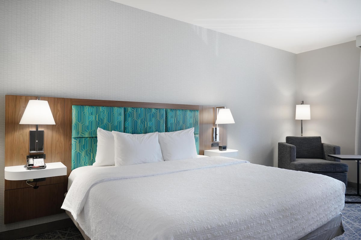Hotellihuone, jossa on suuri sänky, kaksi yöpöytää, tuoli ja työpöytä.