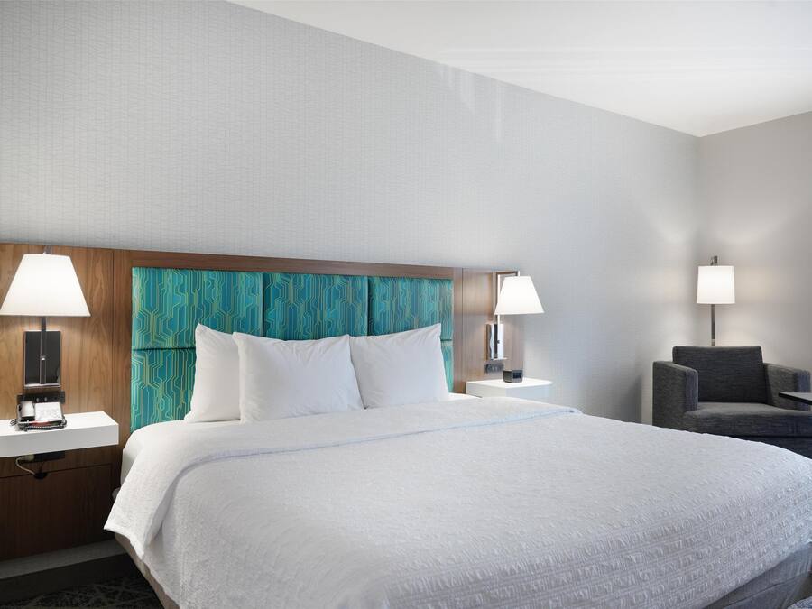 Habitació d'hotel amb un llit gran, dues taules de nit, una cadira i un escriptori.