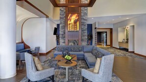 A modern lobby with a stone fireplace, seating area, and a reception desk.