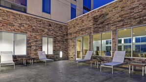 A modern indoor lounge area with stone walls, large windows, and several lounge chairs.