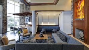 A modern lobby with seating areas, a stone accent wall, and a large window providing a view of the outside.