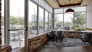 A restaurant with large windows, stone walls, and a black ceiling.
