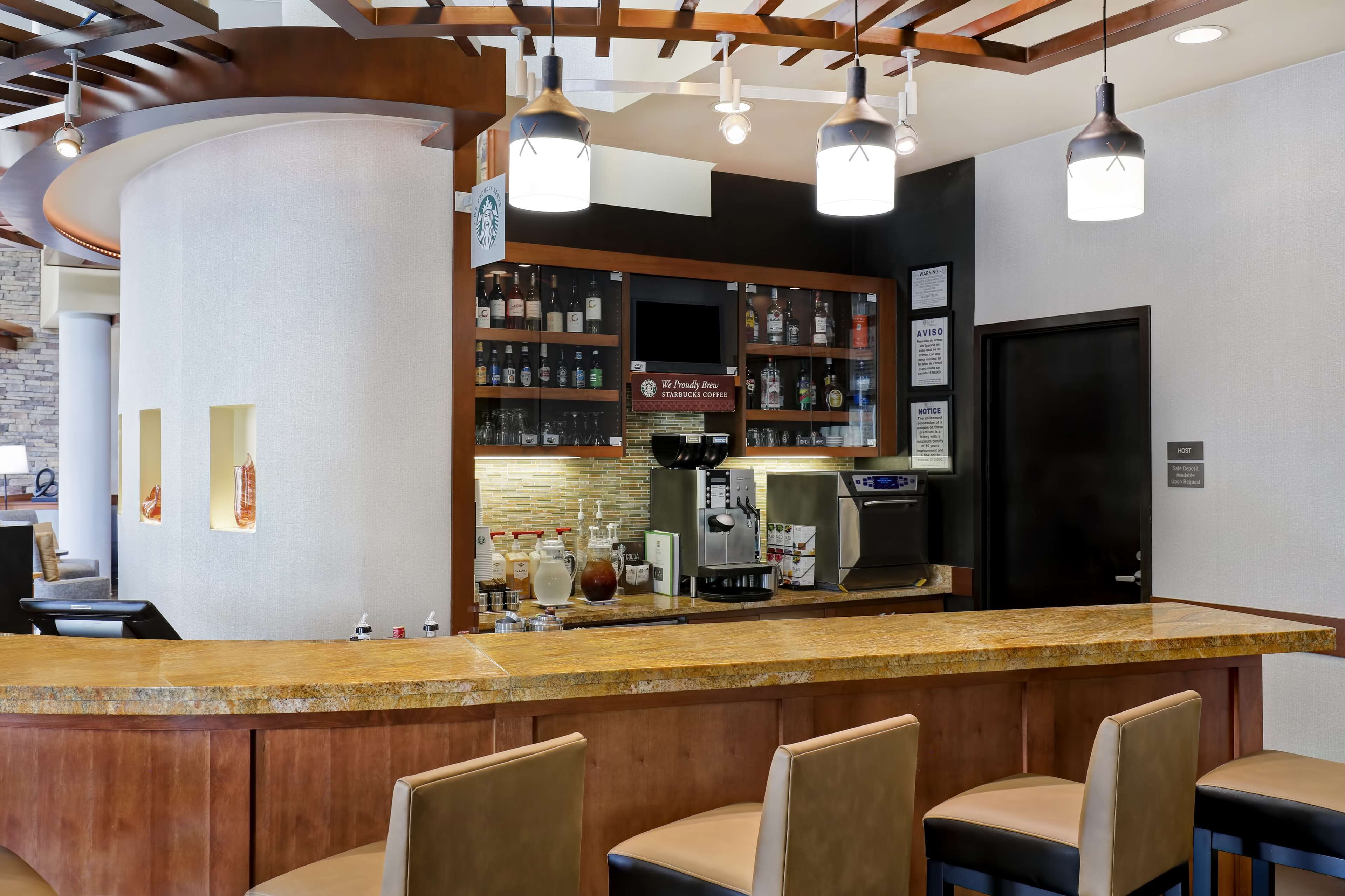 Zona de bar con mostrador, asientos y exhibición de bebidas.