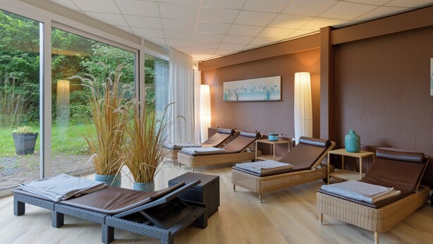 A spa area with three sun loungers, a large window, and a painting on the wall. - Sunday Hotel des Nordens (Harrislee)