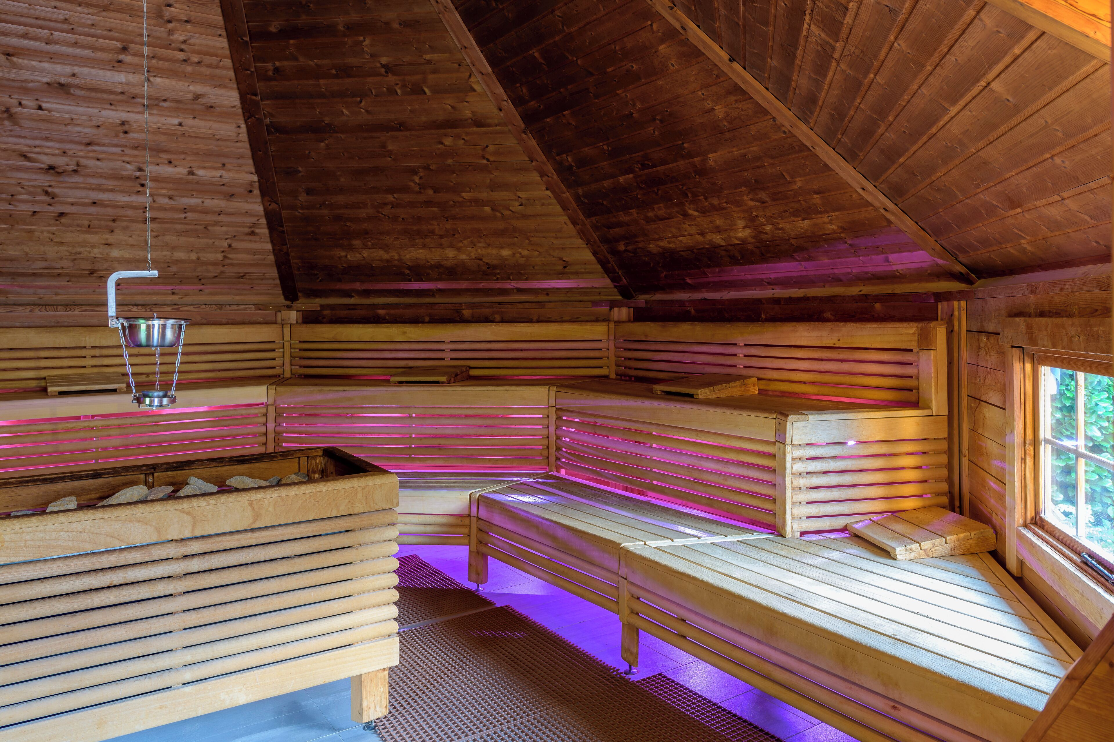 Una sauna de madera con bancos y una lámpara colgante.