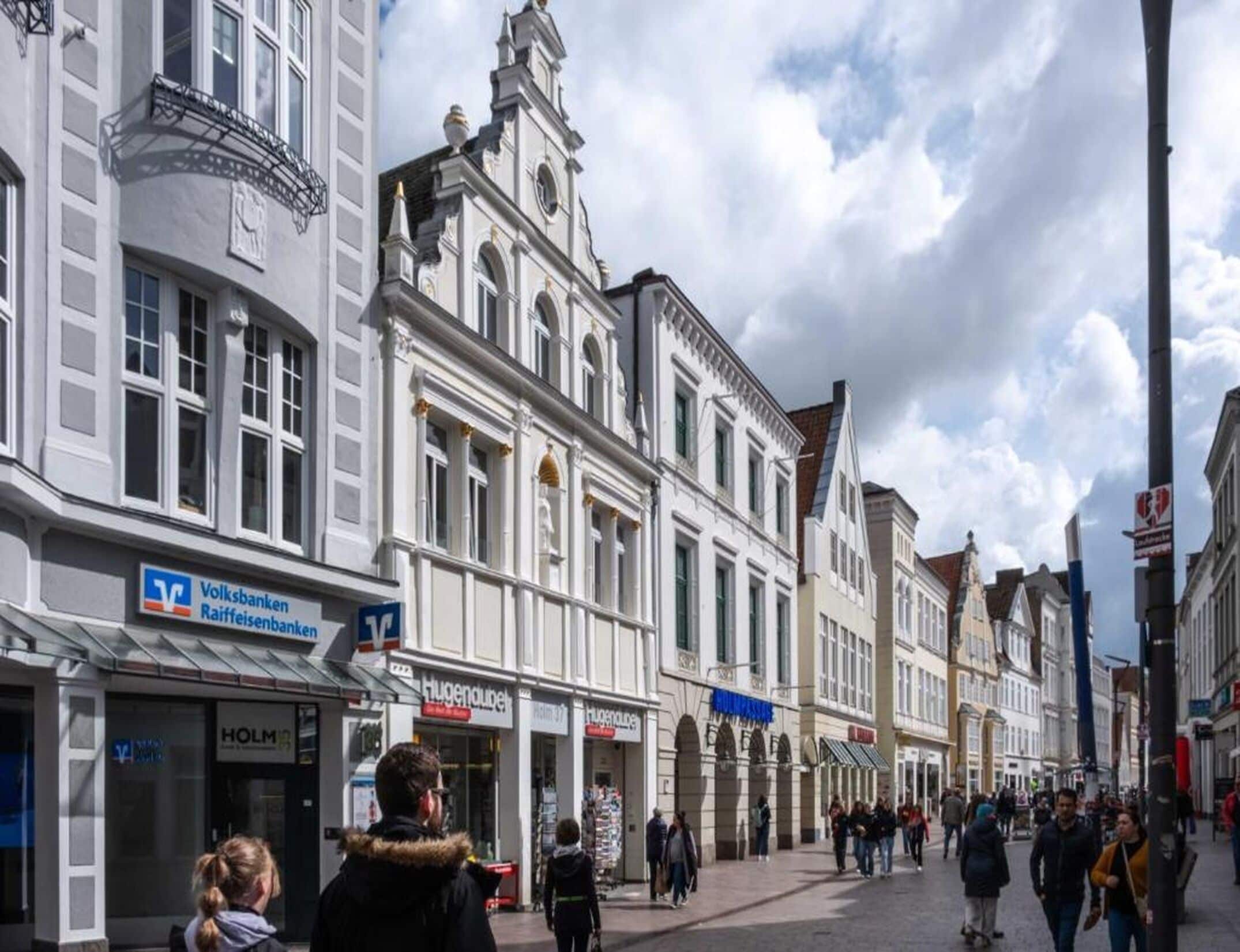 Calle con edificios históricos, una sucursal de Volksbank y una tienda Hugenberg.
