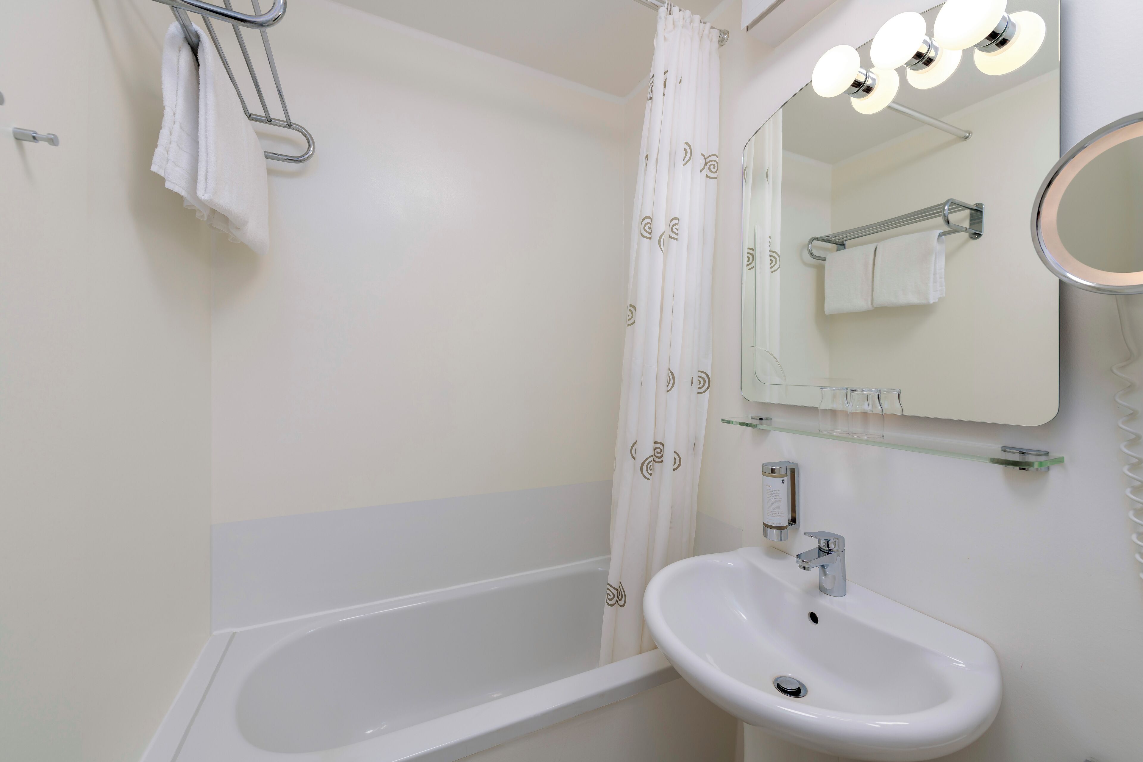 Ein Badezimmer mit Badewanne, Waschbecken, Spiegel und Duschvorhang.
