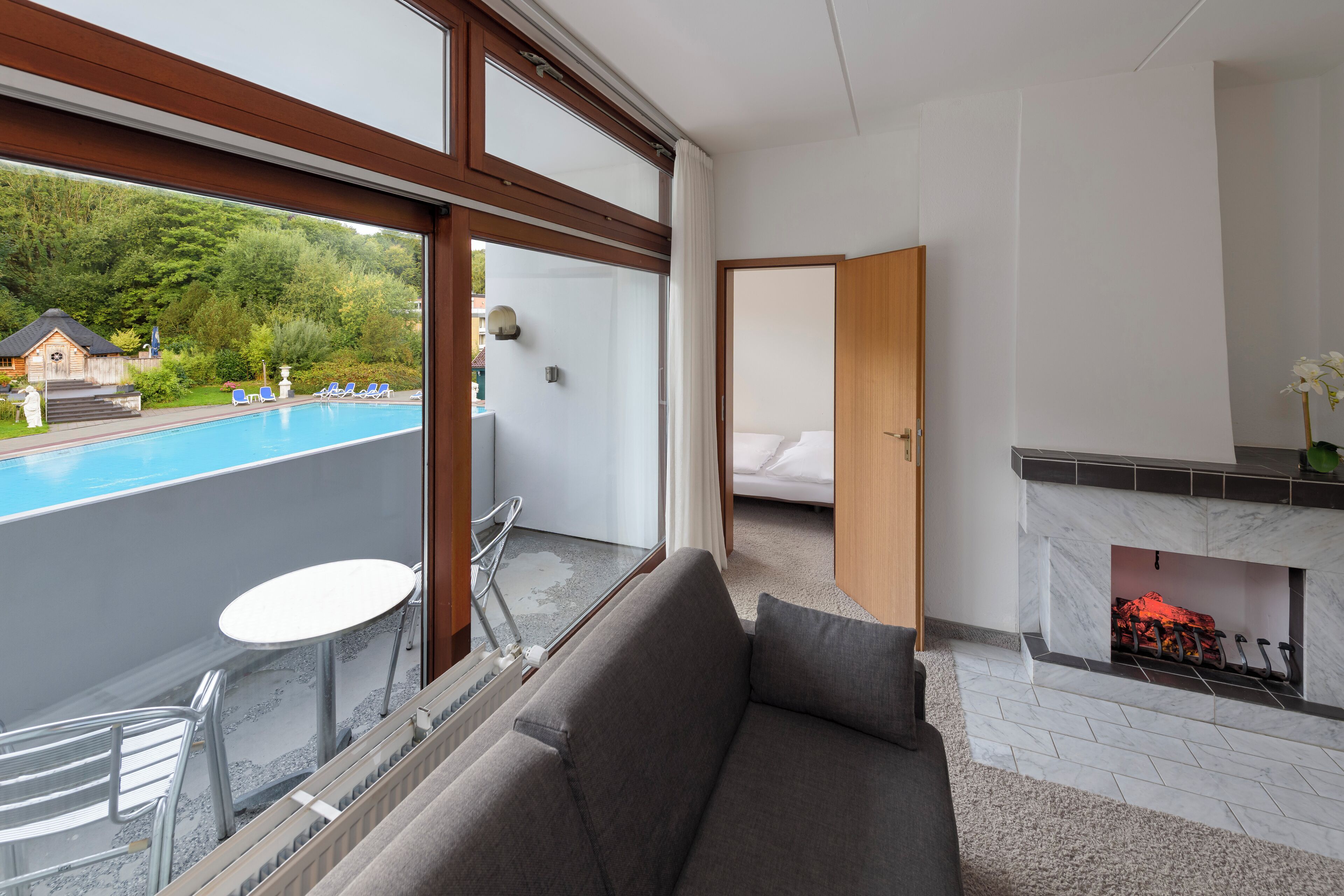 A modern room with a balcony, a fireplace, and a pool view.