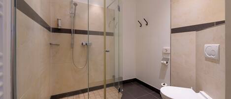 A modern bathroom with a glass-enclosed shower, a white toilet, and a towel rack.