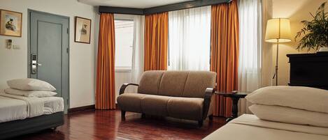A hotel room with a bed, a sofa, a small table, and a lamp.