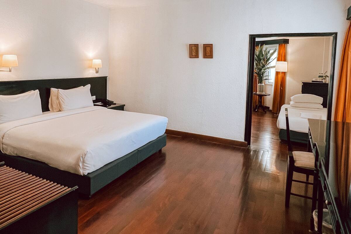 Een hotelkamer met een groot bed, nachtkastjes, een bureau met een stoel en een spiegel.