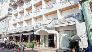 Un hotel de varios pisos con fachada blanca, balcones y una sombrilla exterior con la marca Coca-Cola.