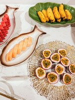 Una mesa con varias fuentes de fruta, incluyendo sandía, maracuyá y plátanos.