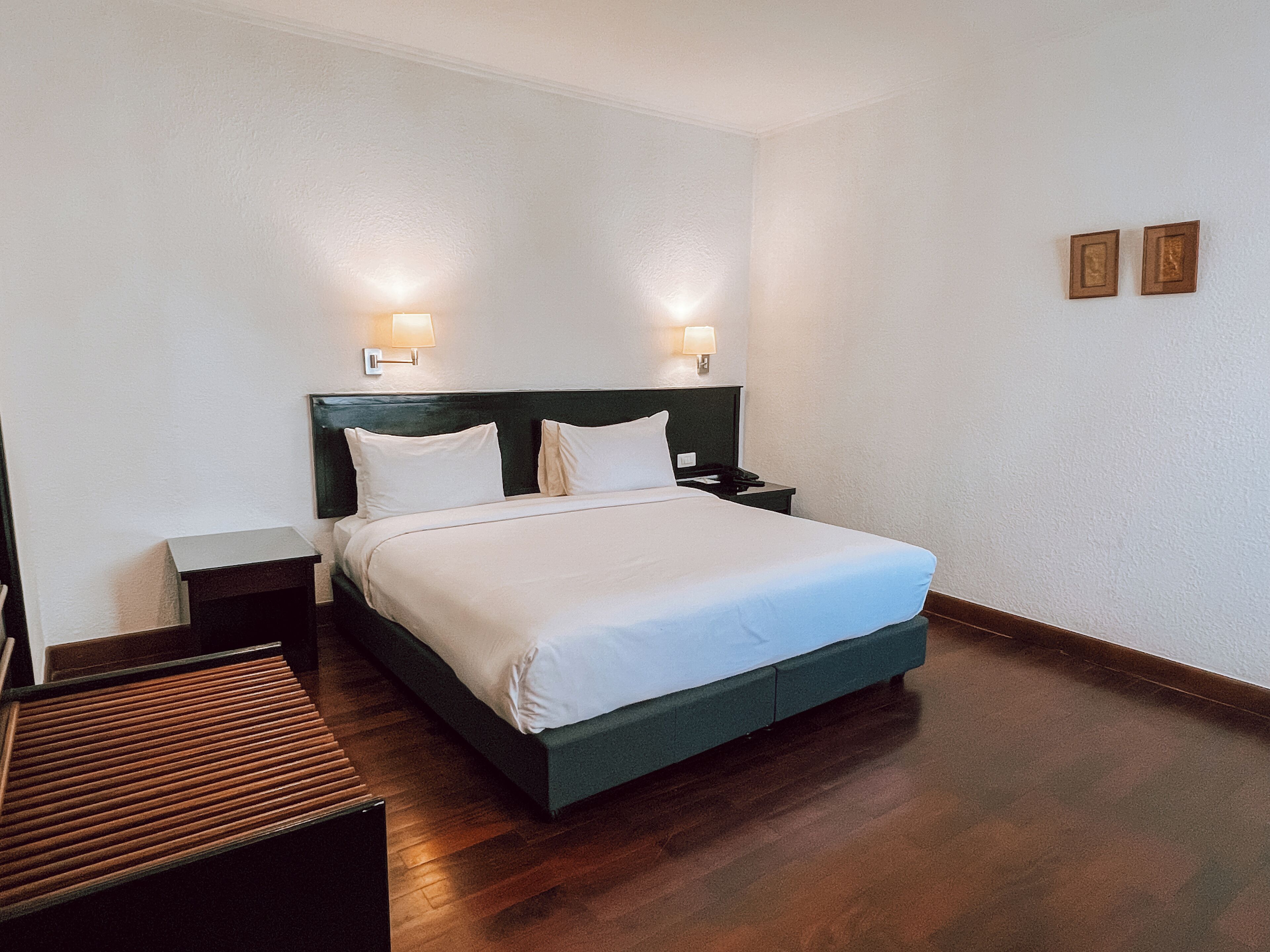 Habitación de hotel impecable con una cama grande, mesitas de noche y lámparas fijadas a la pared.
