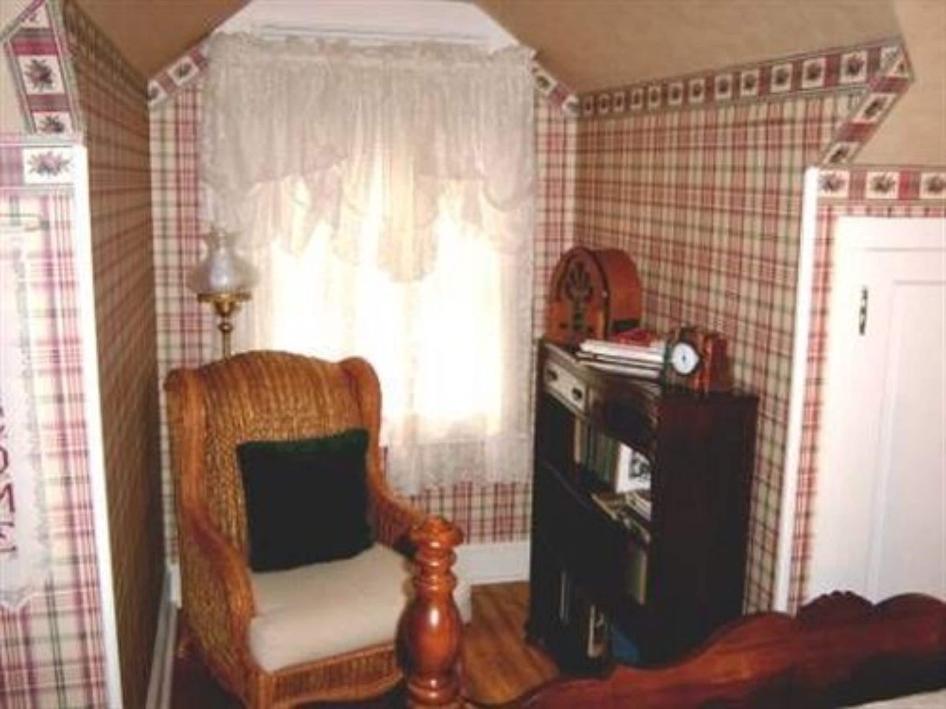 A corner room with a wicker chair, a wooden cabinet, and a white door.