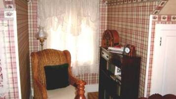 A corner room with a wicker chair, a wooden cabinet, and a white door.
