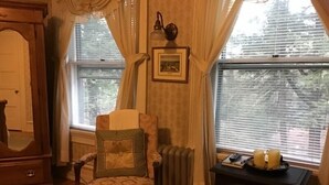 A cozy room with a wooden chair, a fireplace, and a radiator. - Brookview Manor Inn (Canadensis)