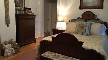 Un dormitorio con una cama de madera, una mesita de noche con lámpara, un aparador y un banco.