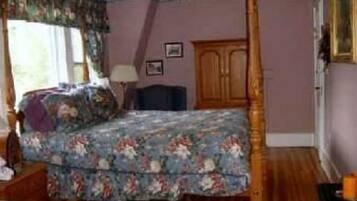 Ein Schlafzimmer mit Himmelbett, Holzboden und Deckenventilator.