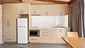 Una cucina moderna con mobili chiari in legno, un frigorifero bianco, un forno e un tavolo da pranzo con sedie.