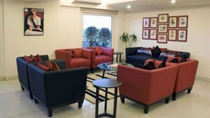 A modern living room with red and blue sofas, a coffee table, and framed pictures on the wall. - Red Fox by Lemon Tree Hotels, Jaipur (Jaipur)