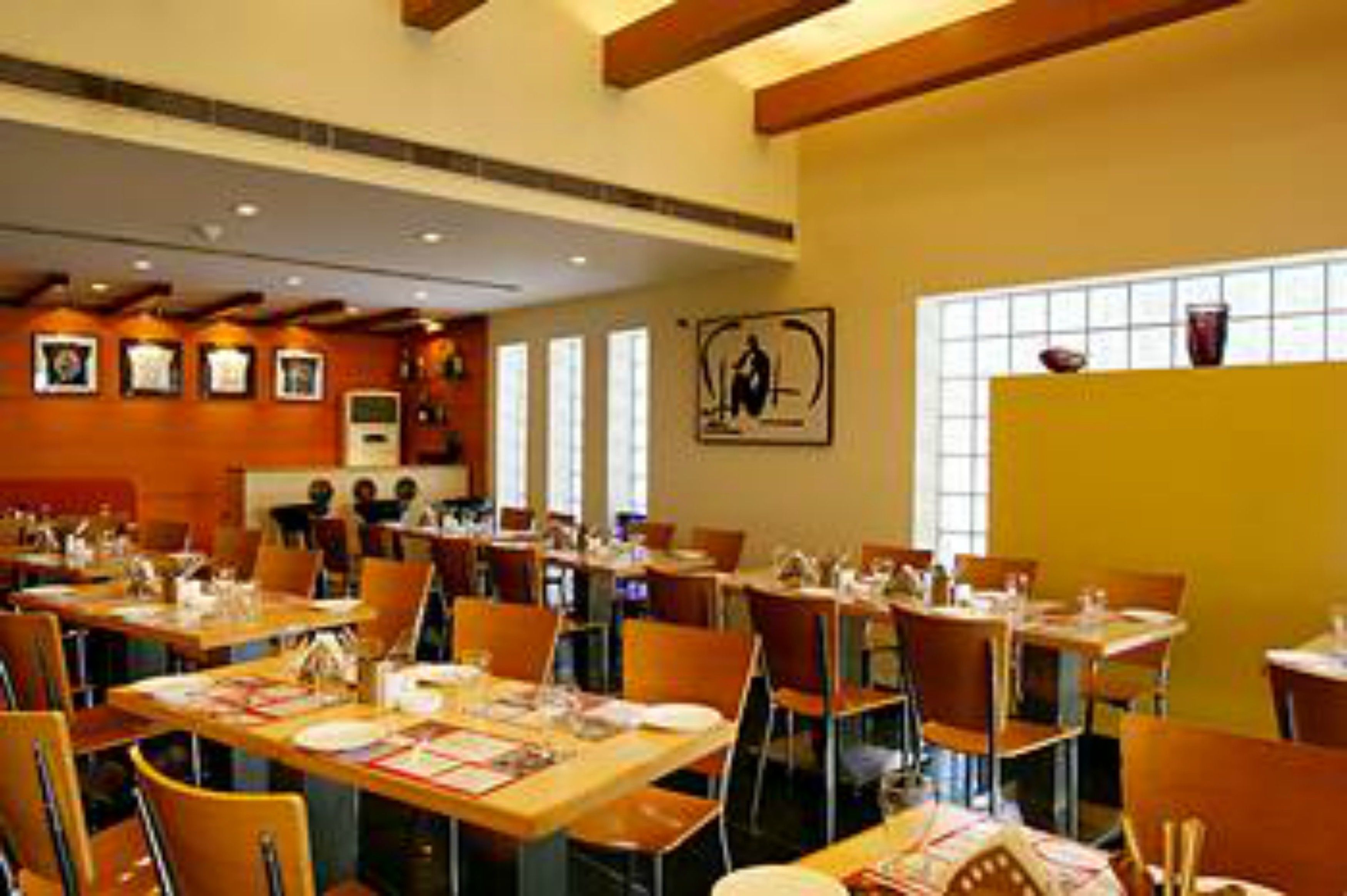 Un restaurante con varias mesas y sillas, techo de madera y cuadros en las paredes.