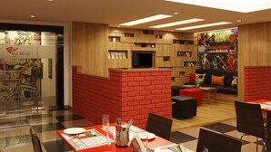 A modern restaurant with a red brick accent wall, wooden shelves, and a large mural. - Red Fox by Lemon Tree Hotels, Jaipur (Jaipur)