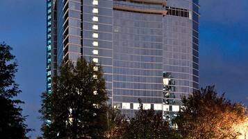 A modern high-rise building with a glass facade, surrounded by trees and a well-maintained lawn.